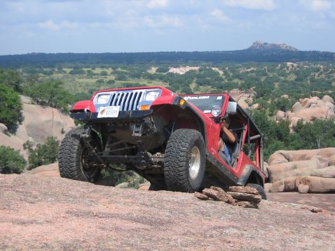 2001 Jeep Wrangler - A red Jeep Wrangler navigates a rocky terrain, demonstrating its off-road capabilities.