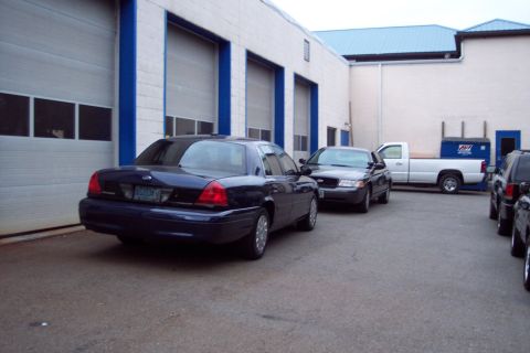 2001 Ford Crown Victoria - A dark blue 2001 Ford Crown Victoria is parked in front of a commercial building with multiple garage doors.