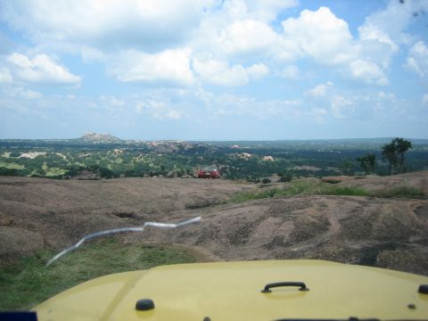 2001 Jeep Wrangler - View from a yellow vehicle looking out over a rocky terrain towards a red car parked in the distance.