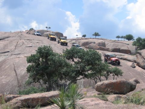 2001 Jeep Wrangler - A group of Jeeps navigates a challenging, rocky terrain on a sunny day with scattered clouds.