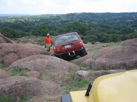 2001 Jeep Wrangler - A red Jeep Grand Cherokee maneuvers through a challenging rocky landscape, with another vehicle visible in the foreground.