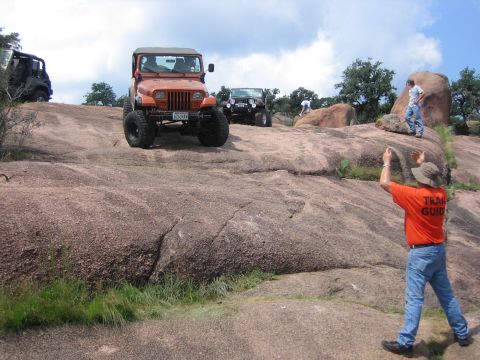 2001 Jeep Wrangler - Several Jeeps navigate a rocky trail under a partly cloudy sky.