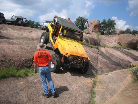 2001 Jeep Wrangler - A yellow Jeep Wrangler navigates a steep, rocky trail with other vehicles nearby.