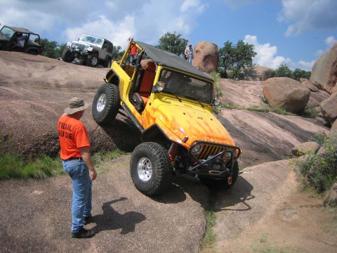 2001 Jeep Wrangler - A yellow Jeep Wrangler navigates a steep, rocky incline with other vehicles and spectators present.