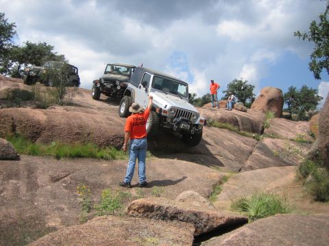 2001 Jeep Wrangler - A group of Jeep Wranglers navigate a challenging rocky terrain, with a trail guide directing the lead vehicle.