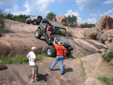 2001 Jeep Wrangler - Two Jeeps navigate a challenging rocky trail under a partly cloudy sky.