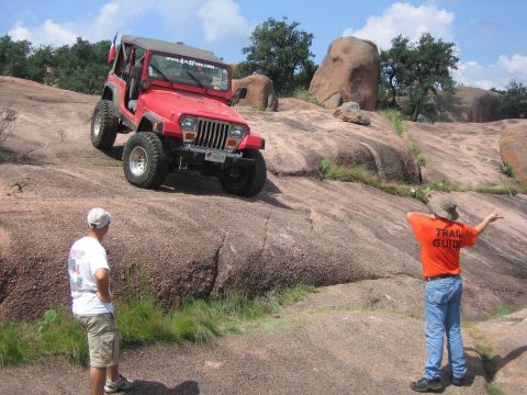 2001 Jeep Wrangler - A red 2001 Jeep Wrangler navigates a steep, rocky terrain during an off-road event.