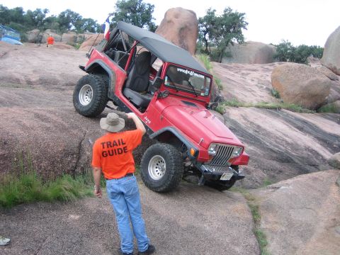 2001 Jeep Wrangler - A red Jeep Wrangler navigates a steep, rocky incline with a trail guide observing its progress.