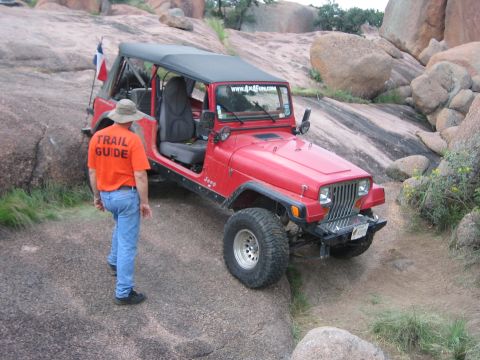 2001 Jeep Wrangler - A red Jeep Wrangler navigates a rocky trail with its driver's side door open.