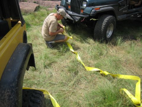 2001 Jeep Wrangler - Two Jeep Wranglers are connected by a yellow tow strap in a grassy, outdoor area.