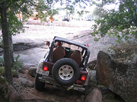 2001 Jeep Wrangler - A 2001 Jeep Wrangler tackles a challenging off-road course with other vehicles visible in the background.
