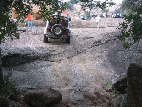 2001 Jeep Wrangler - Several Jeeps are parked on a large, rocky terrain, with trees framing the scene.