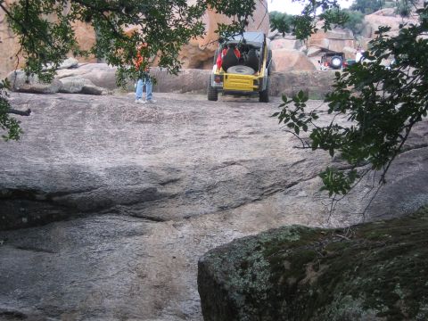 2001 Jeep Wrangler - A yellow Jeep Wrangler is parked on a rocky terrain, with another vehicle visible in the background.