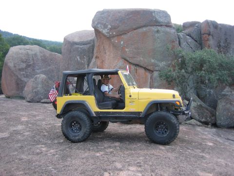 2001 Jeep Wrangler - Driver in a yellow 2001 Jeep Wrangler parked on a large rock formation.