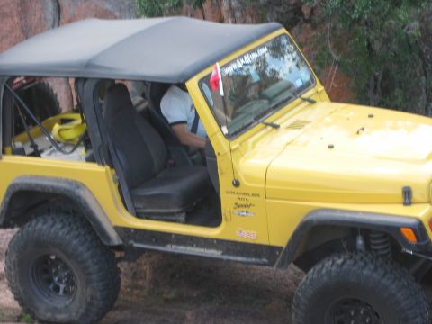 2001 Jeep Wrangler - Yellow 2001 Jeep Wrangler TJ with soft top and off-road tires parked outdoors.
