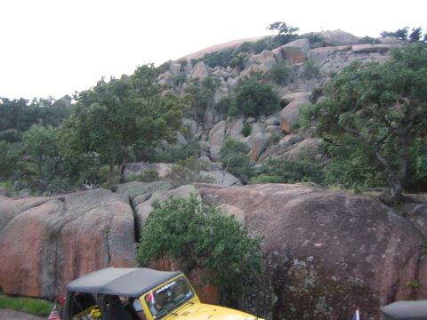 2001 Jeep Wrangler - A yellow Jeep Wrangler is parked on a rocky hill with trees and boulders.