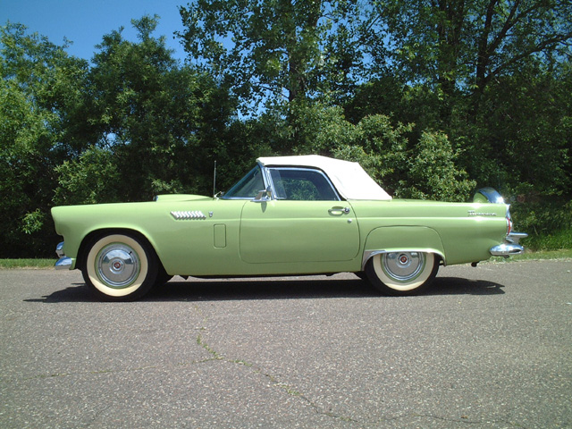 Side view of a light green 1955 Ford Thunderbird convertible with a white soft top
