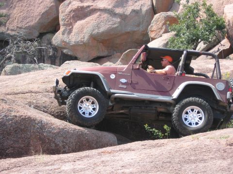 2001 Jeep Wrangler - A maroon 2001 Jeep Wrangler navigates a rocky terrain during an off-road excursion.
