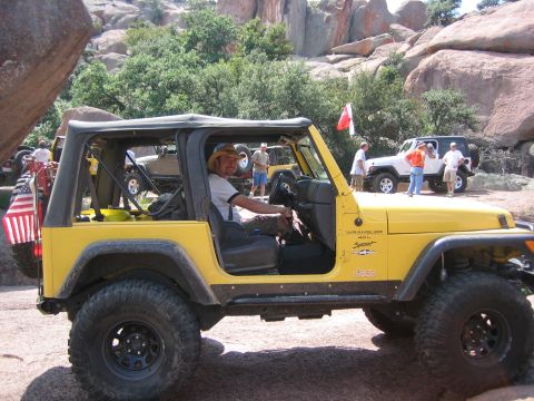 2001 Jeep Wrangler - A group of Jeeps are gathered on a rocky trail, with one yellow Jeep Wrangler in the foreground.
