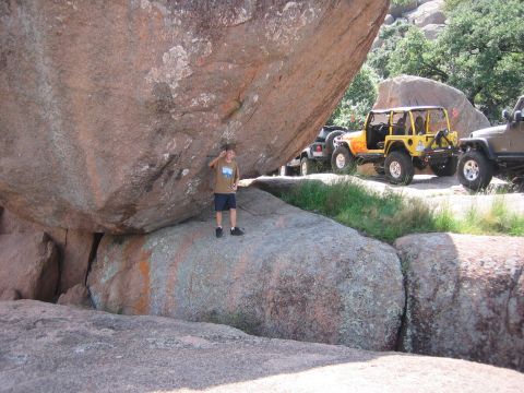 2001 Jeep Wrangler - A group of Jeeps, including a yellow Wrangler, are parked on a rocky trail while a boy stands under a massive boulder.