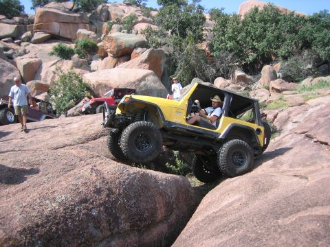 2001 Jeep Wrangler - A yellow 2001 Jeep Wrangler tackles a challenging rocky terrain during an off-road event.