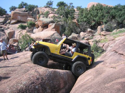 2001 Jeep Wrangler - A yellow 2001 Jeep Wrangler tackles a challenging rocky trail during an off-road event.
