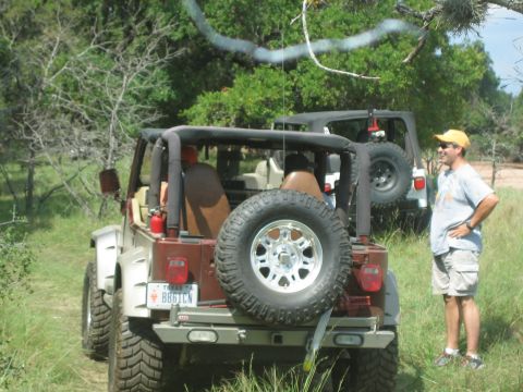 2001 Jeep Wrangler - Two Jeeps are parked off-road in a natural setting, with a man standing nearby.