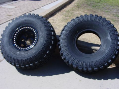 1994 Ford Bronco - Two off-road tires are displayed, with one mounted on a black beadlock wheel. The tires feature aggressive tread patterns suitable for terr…