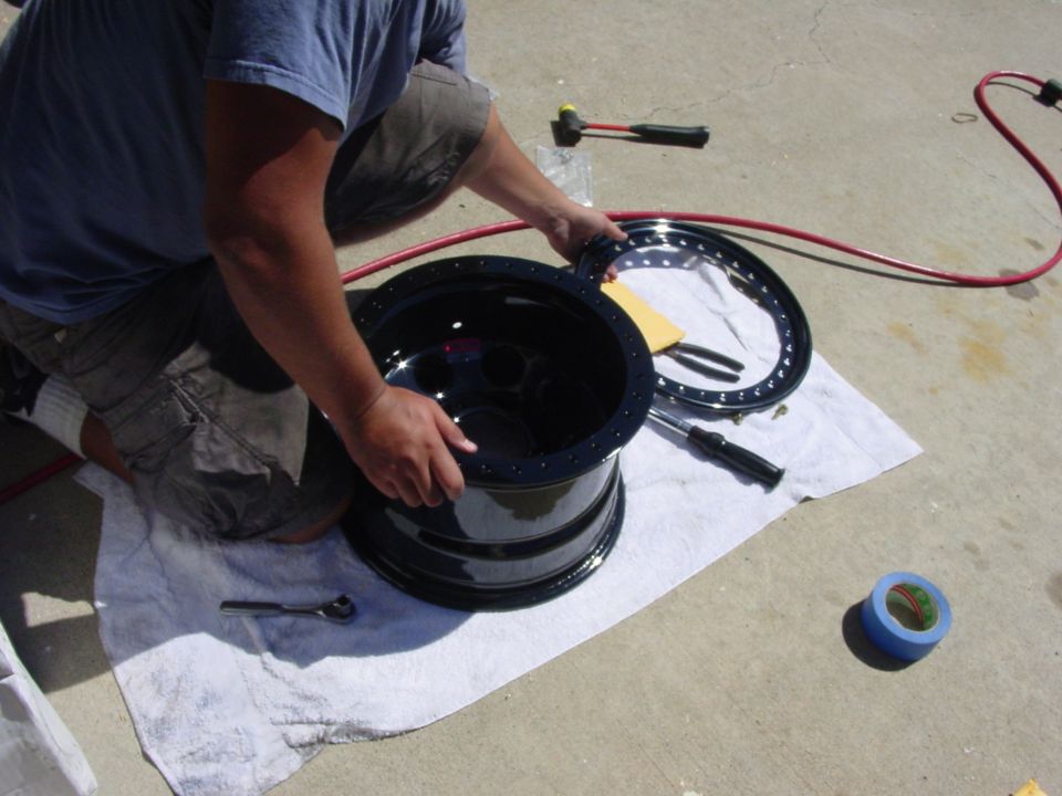 Person assembling a black wheel rim with tools and tape