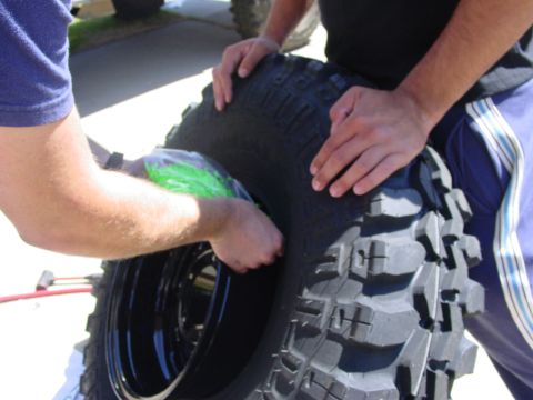 1994 Ford Bronco - Hands are seen manipulating a tire and rim, possibly for repair or installation.