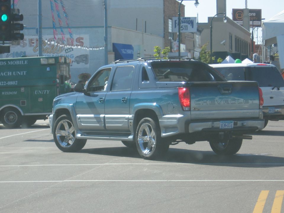 Blue Chevrolet Avalanche with chrome wheels, rear view