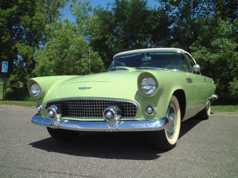 1956 Ford Thunderbird - A light green 1955 Ford Thunderbird is shown from the front three-quarter view, parked on asphalt with trees behind it.