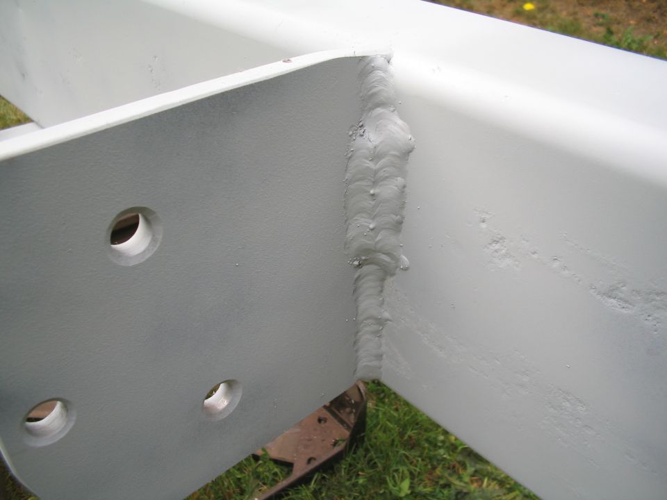 Welded metal bracket with three visible holes and rough weld seams