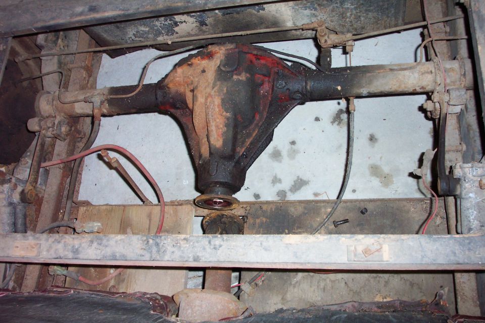 Underside view of rusty rear axle differential housing between frame rails