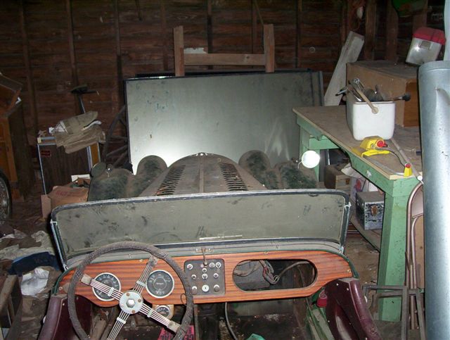 Vintage roadster with wood dash and round gauges stored in cluttered barn