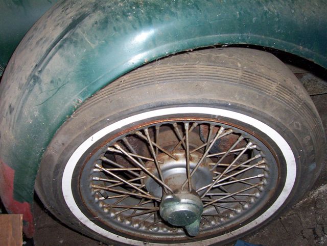 Wire-spoke wheel with knock-off hub and whitewall tire on green fender