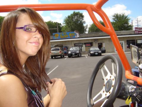 1992 Ford Bronco - A woman poses for a photo in front of a store with several vehicles parked in the lot.