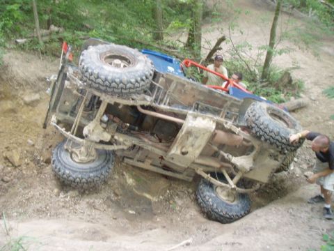 1992 Ford Bronco - An off-road vehicle has overturned on a steep, wooded incline.