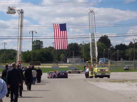 1992 Ford Bronco - A fire truck and police cars are present at an event with a large American flag displayed.