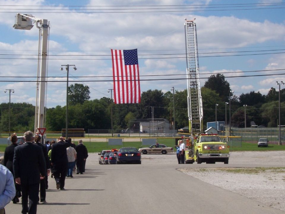 Yellow fire truck with ladder extended, American flag overhead