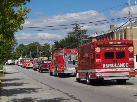 1992 Ford Bronco - A line of Syracuse Fire Department vehicles, including an ambulance and several fire trucks, proceeds down a street under a partly cloudy s…