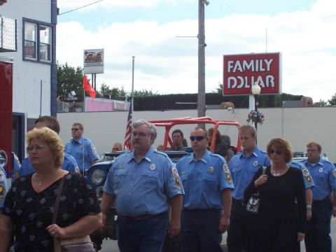 1992 Ford Bronco - A group of people, some in uniform, walk past a red off-road vehicle in front of a Family Dollar store.