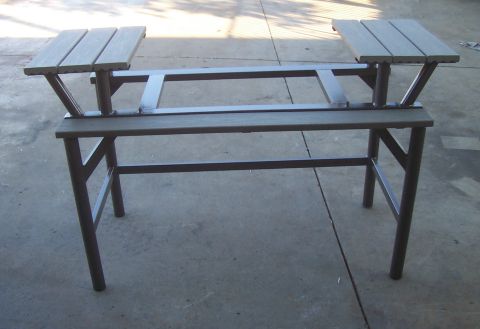 1994 Ford F-150 - A metal table frame with wooden seats is shown from the front, resting on a concrete surface.