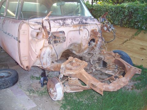 1955 Ford Customline - This vehicle's front end is completely disassembled, revealing a heavily rusted chassis and suspension system.