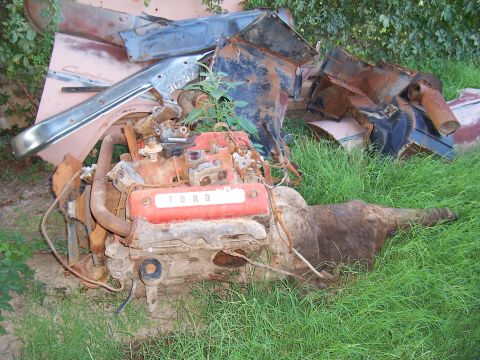1955 Ford Customline - A disassembled Ford V8 engine and transmission lie in the grass amongst other scrap car parts.
