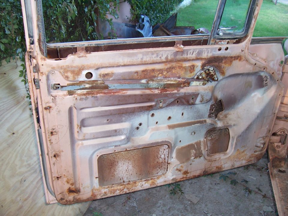Rusted interior of a car door, showing metal panels and mounting points
