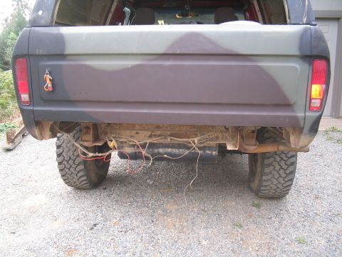 1979 Ford Bronco - Rear view of a camouflage SUV with visible undercarriage details and exposed wiring.