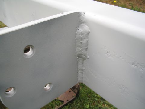 1979 Ford Bronco - This image shows a section of a white painted metal structure with prominent welds and bolt holes.