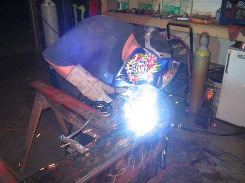 1979 Ford Bronco - Metal beam being welded in a workshop setting with welding equipment visible.