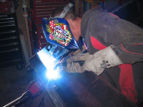 1979 Ford Bronco - A person in protective gear welds metal, creating a shower of bright sparks.